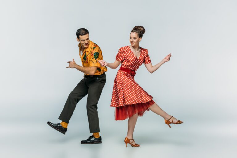 young dancers holding hands while dancing boogie-woogie on grey background